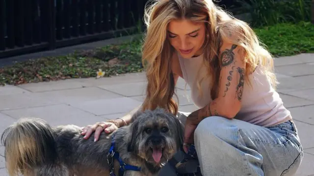 Giuliana Passarelli agachada acariciando a un perro.