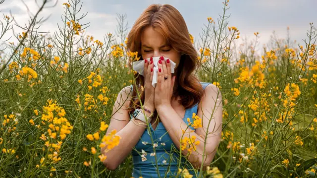 Mujer en el campo estornudando.