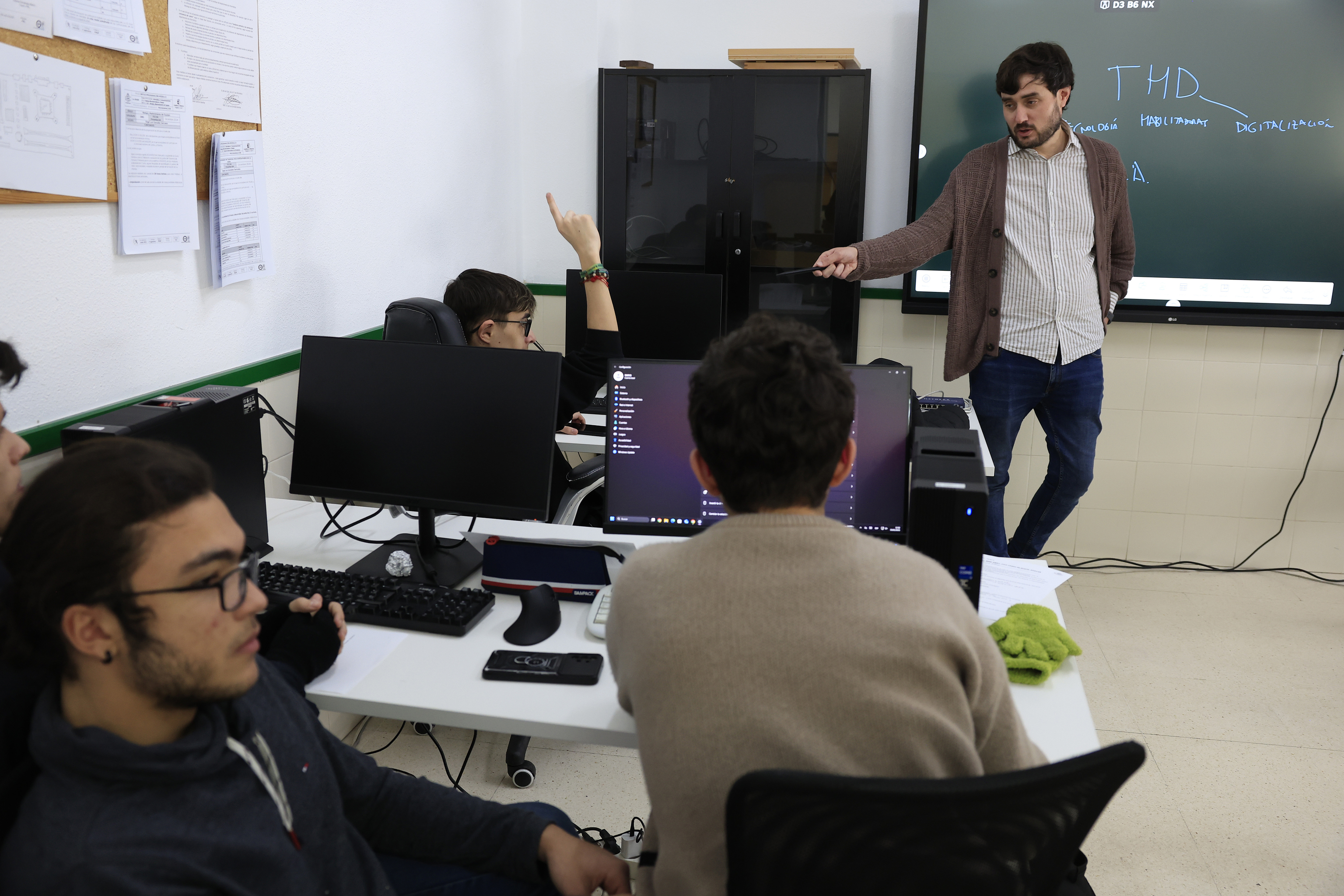 Un profesor atiende a uno de sus alumnos en el aula.