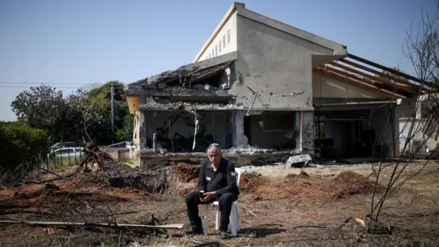 Un hombre está sentado frente a una casa en el centro de Israel que resultó dañada por un proyectil lanzado por Hezbolá desde el Líbano (12 de marzo de 2026)