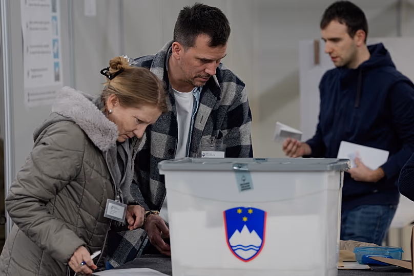 Members of the electoral commission handle ballots at a sports hall turned polling station for early voting in Ljubljana, 18 March, 2026