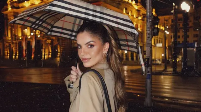Giuliana Passarelli bajo un paraguas en una noche lluviosa.