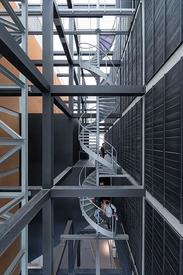 Escalera caracol metálica integrada en una estructura industrial con marcos y pasarelas de acero.