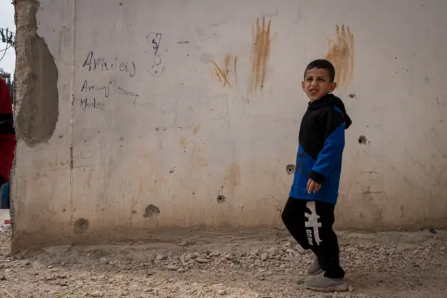 Los agujeros de bala acribillan la pared del campo de refugiados de al-Far'a, en la Cisjordania ocupada, en el lugar donde las cámaras de seguridad muestran cómo Jad es abatido a quemarropa por un soldado israelí. Un niño pequeño aparece en primer plano en la imagen.
