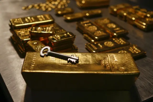 Lingotes de oro de diferente tamaño. Sobre uno de ellos hay una llave. 