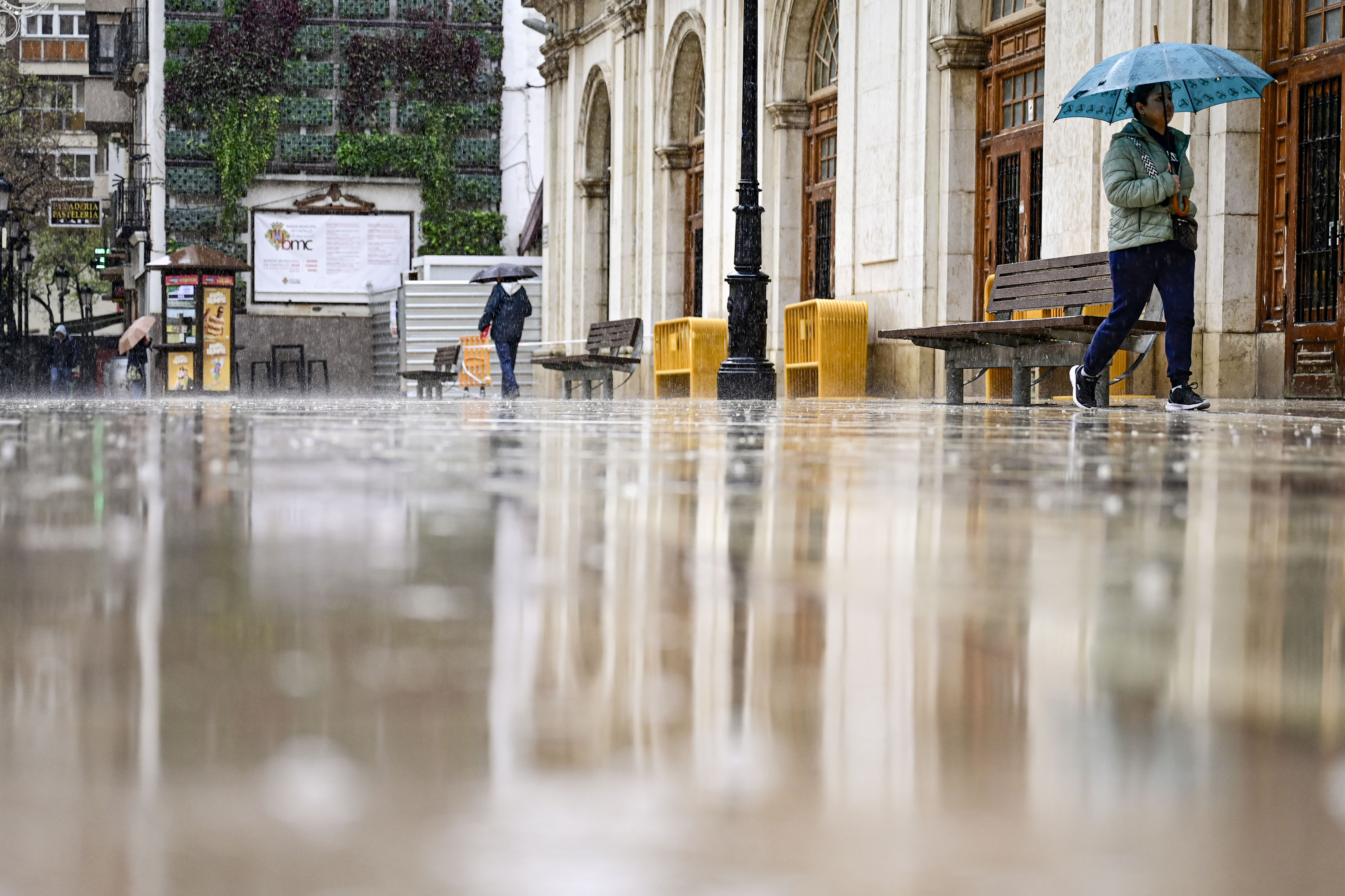Varias personas caminan bajo la lluvia, este viernes, por las calles del centro de Castellón.