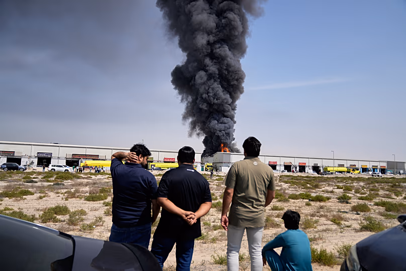 Residents look at flames and plume of smoke rises from a warehouse in the United Arab Emirates following reports of Iranian strikes in Dubai, 1 March 2026.