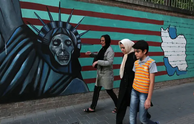 Una familia iraní pasa junto a unas pintadas antiamericanas en la pared de la antigua embajada de Estados Unidos en Teherán. Foto de 2015.