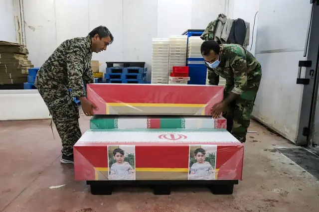Dos militares mueven un ataúd junto a otros dos, uno con fotografías de una niña