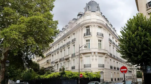 Un gran edificio tradicional parisino en la esquina de una calle, construido con piedra clara.