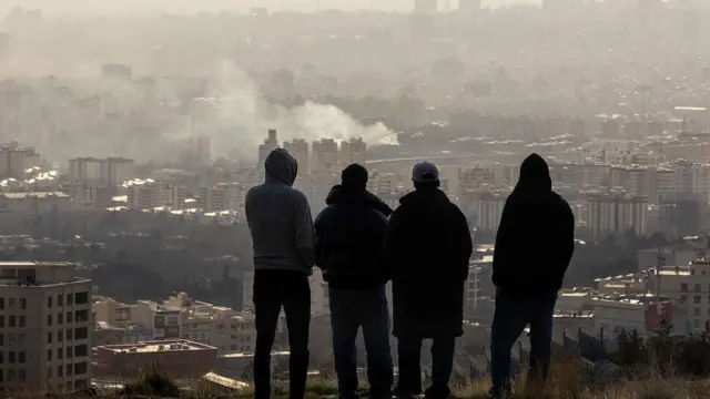 Jovenes miran como la ciudad está afectada por los bombardeos.