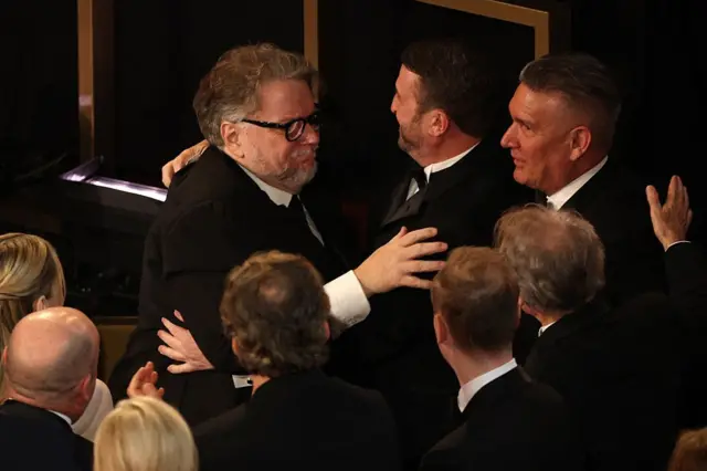 El director y productor mexicano Guillermo Del Toro felicita a los artistas de peluquería y maquillaje Jordan Samuel y Mike Hill después de que ganaran el Óscar a Mejor Maquillaje y Peinado por "Frankenstein" durante la 98ª edición de los Premios de la Academia en el Teatro Dolby en Hollywood, California, el 15 de marzo de 2026. (Foto de Patrick T. Fallon / AFP a través de Getty Images)