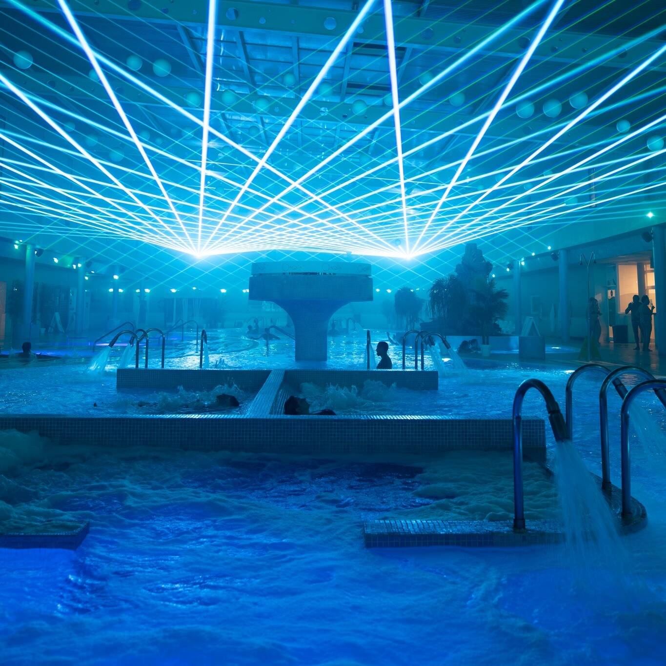 Foto: Un espectáculo de luces láser recorre las piscinas termales y crea una experiencia inmersiva para los visitantes. (Extraída de Facebook)