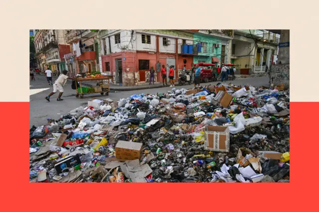 Personas pasan delante de una montaña de basura en La Habana.
