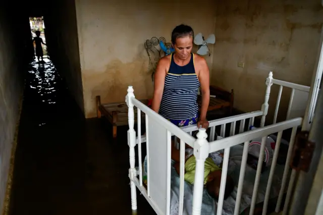 Mujer mira la cuna de una bebé.