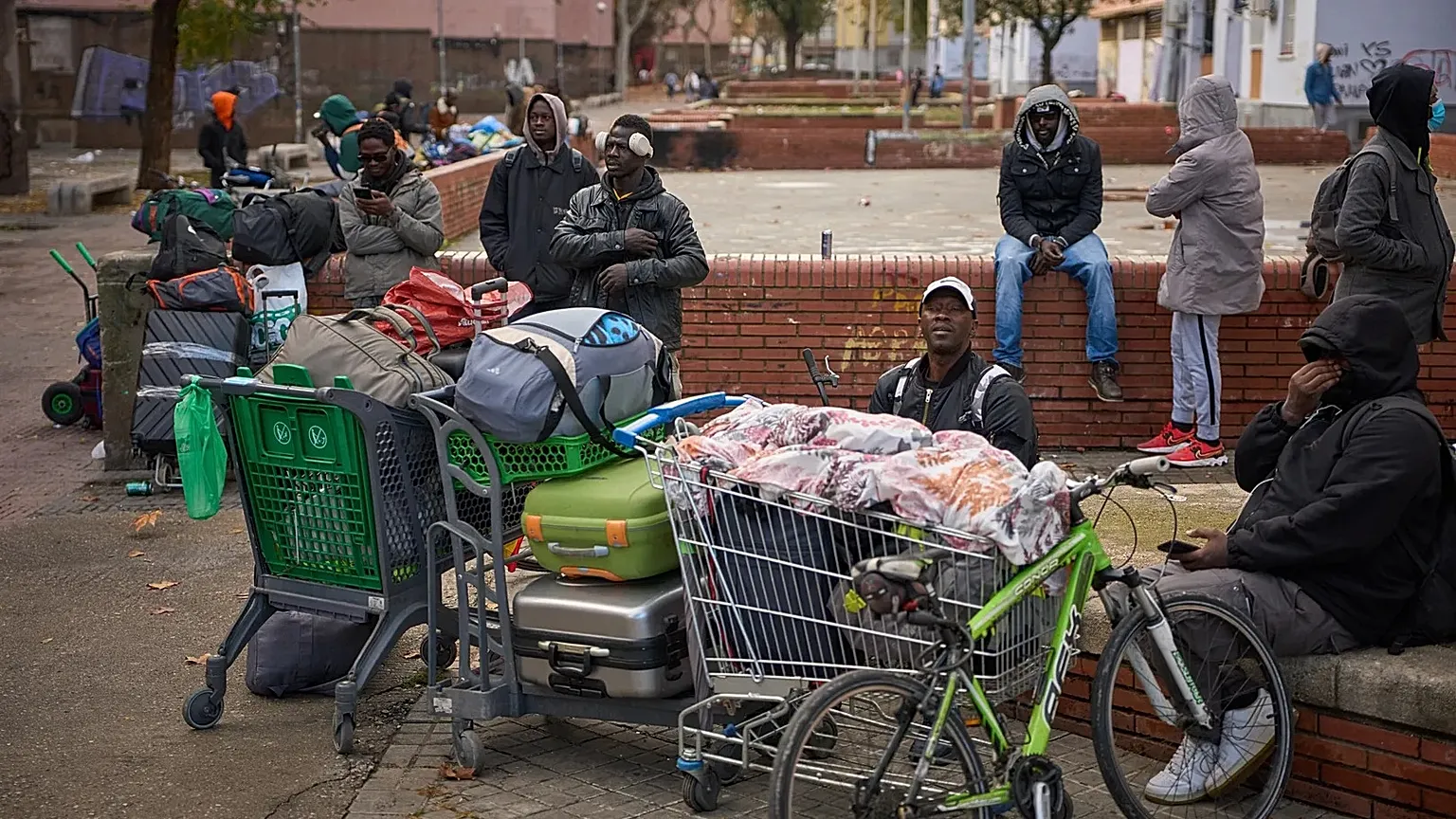 Migrants sit together with their belongings after being evicted by police from an abandoned school where they had been living in Badalona, 17 December, 2025