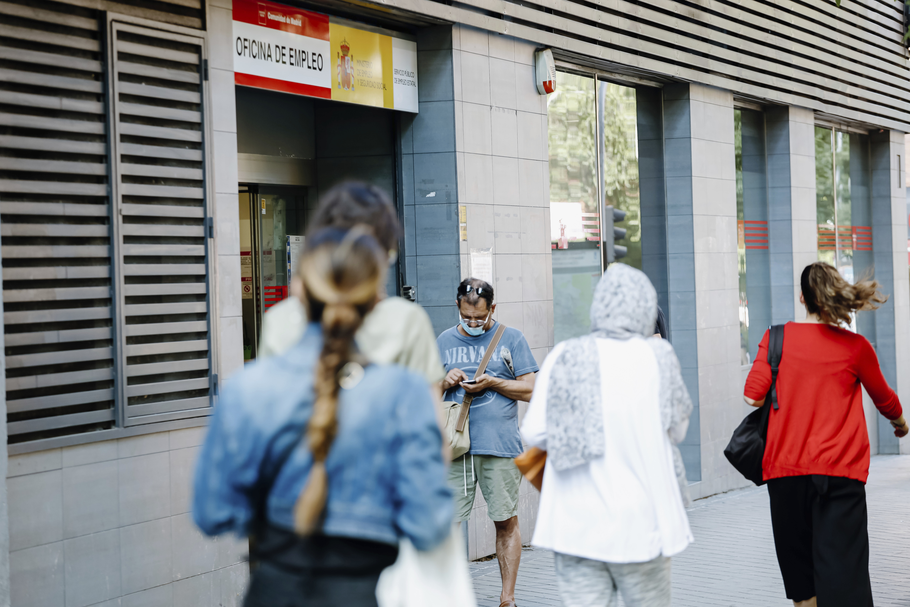 Varias personas caminando frente a una oficina del SEPE en Madrid.