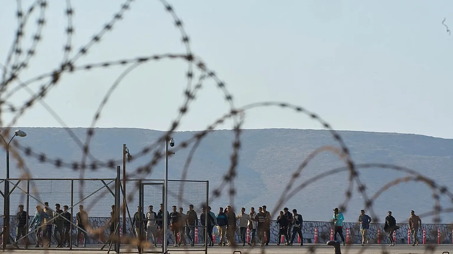 Migrants rescued south of Crete walk after their arrival at the port of Lavrio, 10 July, 2025