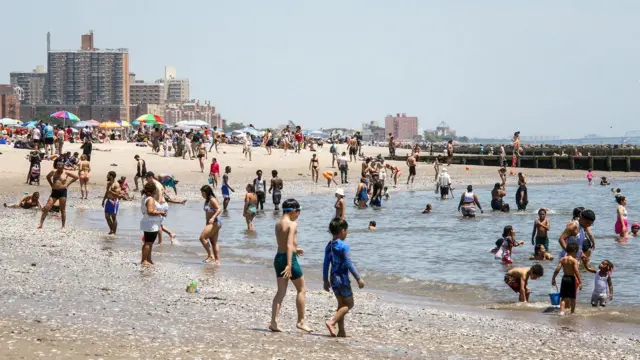 Playa con arena y piedras, y mucha gente