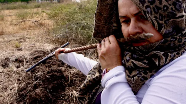 Reynalda Pulido, que lleva un pañuelo con estampado animal alrededor de la cabeza para protegerse del sol, huele una varilla de metal que acaba de sacar del suelo.