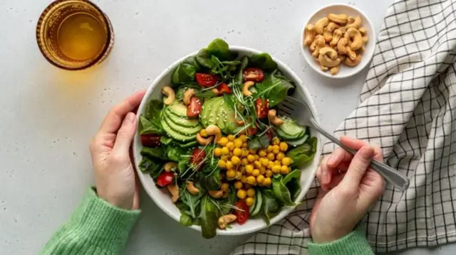 Un tazón de comida con muchas verduras.