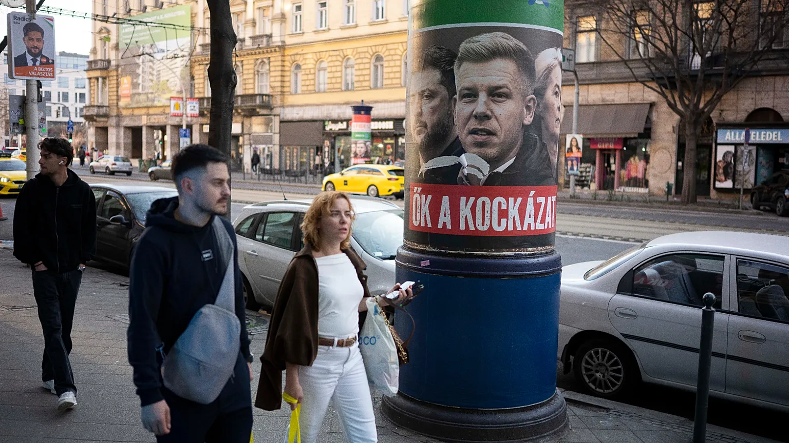 People walk next to a campaign poster which says, "They're a risk. Fidesz is the safe choice" in Budapest, Hungary, on 14 March, 2026, ahead of the parliamentary elections.