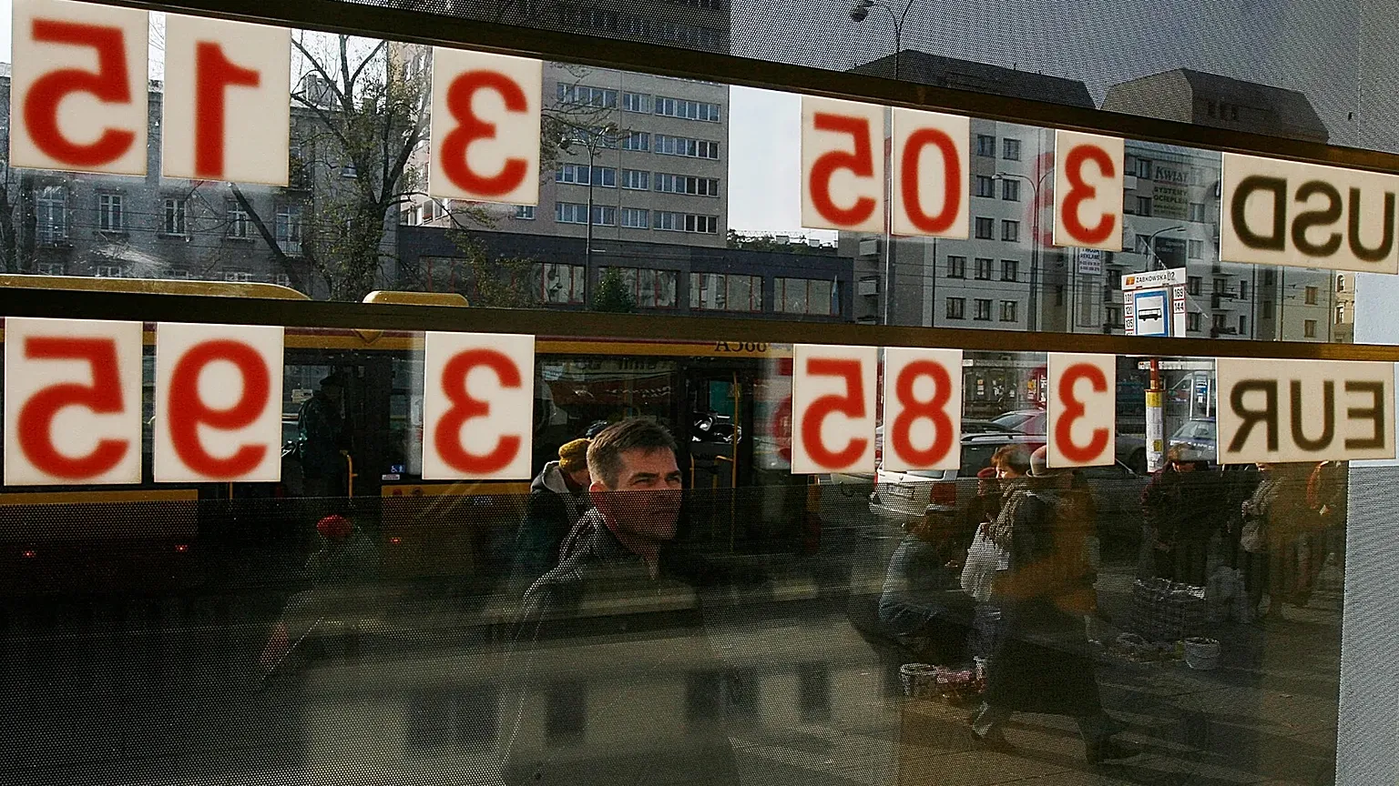 A man checks the local currency exchange rate to the US dollar and the euro in Warsaw, 24 October, 2008