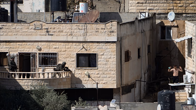 A man holds his hand while in the sight of two Israeli soldiers in the West Bank town of Qabatiya during a raid, Thursday, Sept.19, 2024. (AP Photo/Majdi Mohammed)