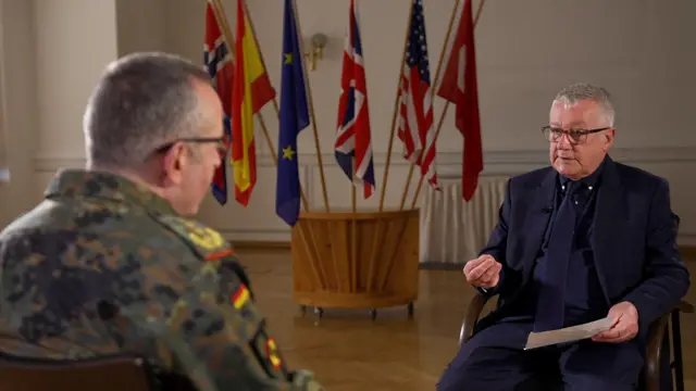 El general Carsten Breuer en sus fatigas militares sentado frenta a Allan Little, vestido con un traje oscuro.