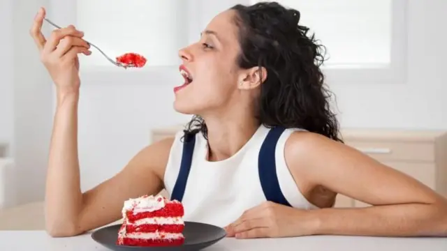 Una mujer comiendo pastel.