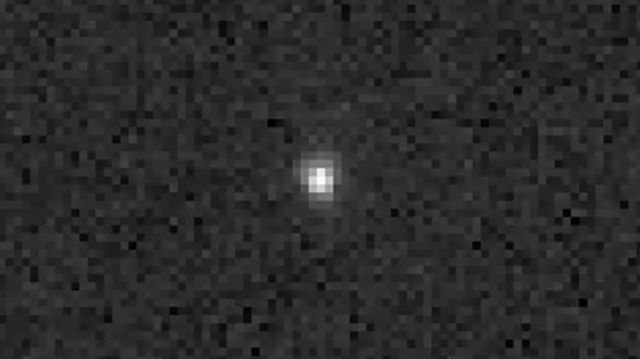 Un grupo de píxeles blancos forma un punto blanco en el centro de la imagen sobre un fondo negro y gris muy pixelado.