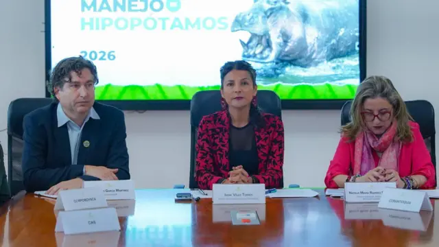 La ministra de Ambiente encargada (en el centro) sentada en una mesa durante el anuncio del plan del gobierno para reducir la población de hipopótamos.