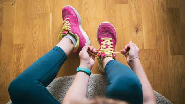 Una persona con pantalones de gimnasia azules se ata las zapatillas de deporte