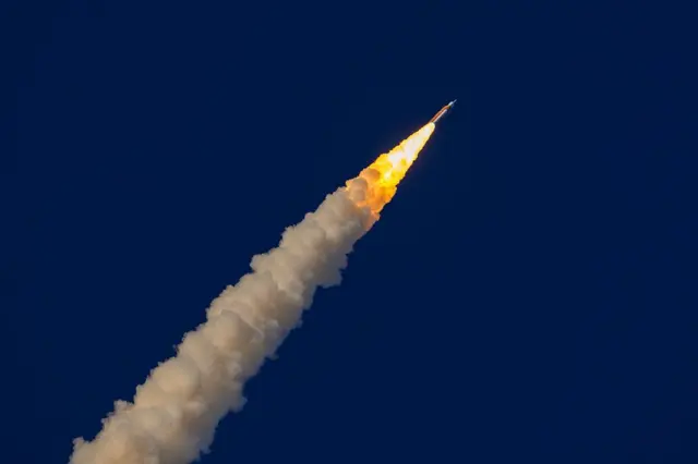 El cohete con cola de fuego y humo en el cielo azul oscuro