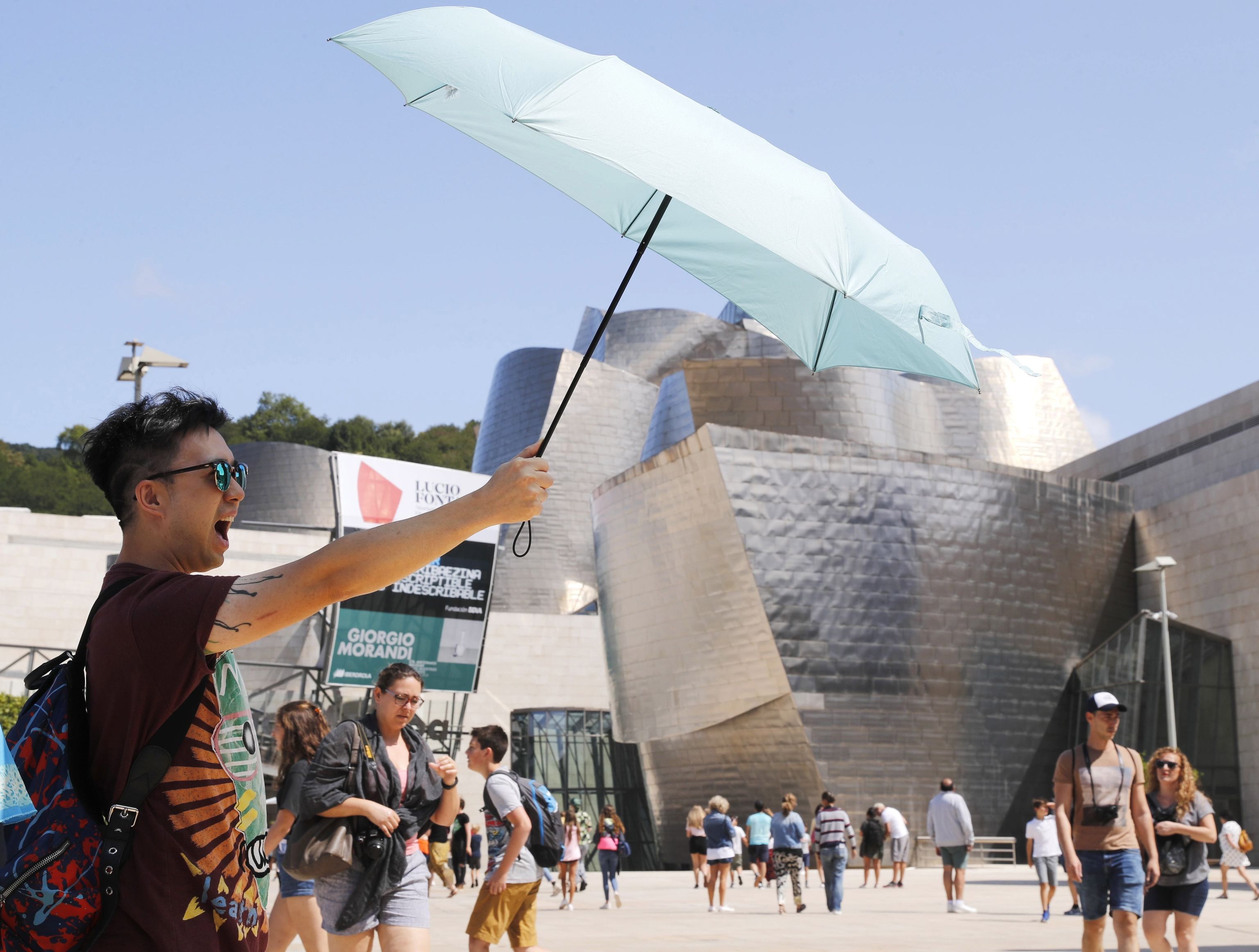 Un turista se protege del sol ante el museo Guggenheim de Bilbao.