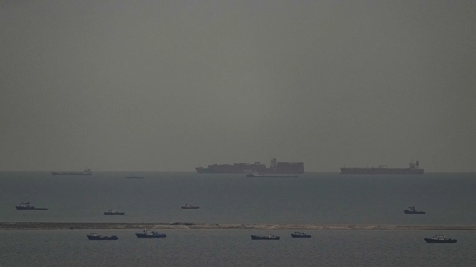 Fishing boats dot the sea as cargo ships, in the background, sail through the Arabian Gulf toward the Strait of Hormuz off the United Arab Emirates, Friday, March 27, 2026. 