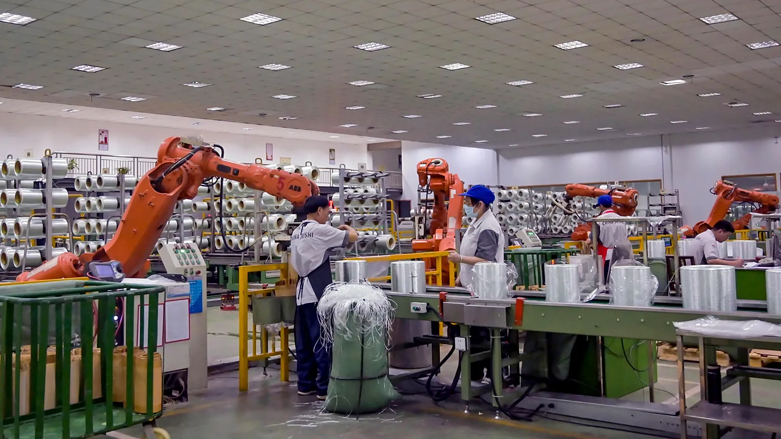 In this July 15, 2019, photo, workers wrap glass fiber rolls next to the robot arms at a factory in Jiujiang in central China's Jiangxi province. July 31, 2019.