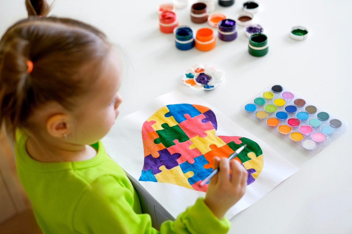 Una niña pinta un corazón de colores (AdobeStock)