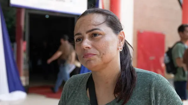 Marluize Avila, una mujer de piel trigueña y cabello liso, frente a la entrada de un edificio.