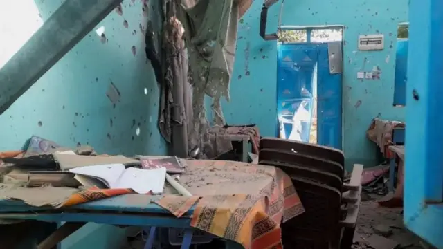 Un salón de clase destruido con las paredes perforadas por balas