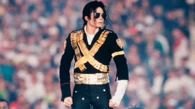 El cantante Michael Jackson, vistiendo un traje negro y dorado, actúa en el espectáculo del medio tiempo del Super Bowl XXVII en Pasadena, California, en 1993.