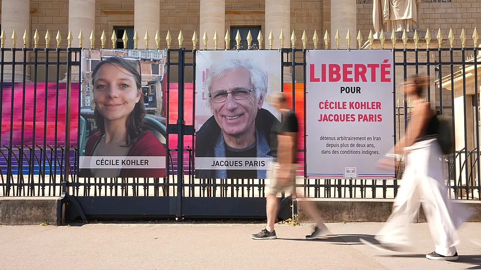 People walk past the portraits of French nationals Cécile Kohler and Jacques Paris in front of the French National Assembly in Paris, 3 July, 2025