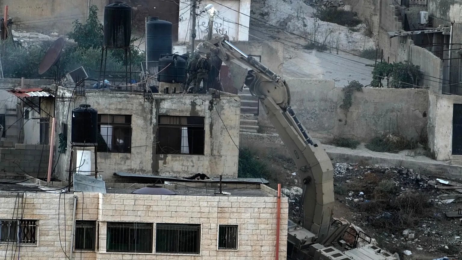 Israeli soldiers look over a rooftop where two bodies lie motionless in the West Bank town of Qabatiya during a raid, Thursday, Sept. 19, 2024. (AP Photo/Majdi Mohammed)
