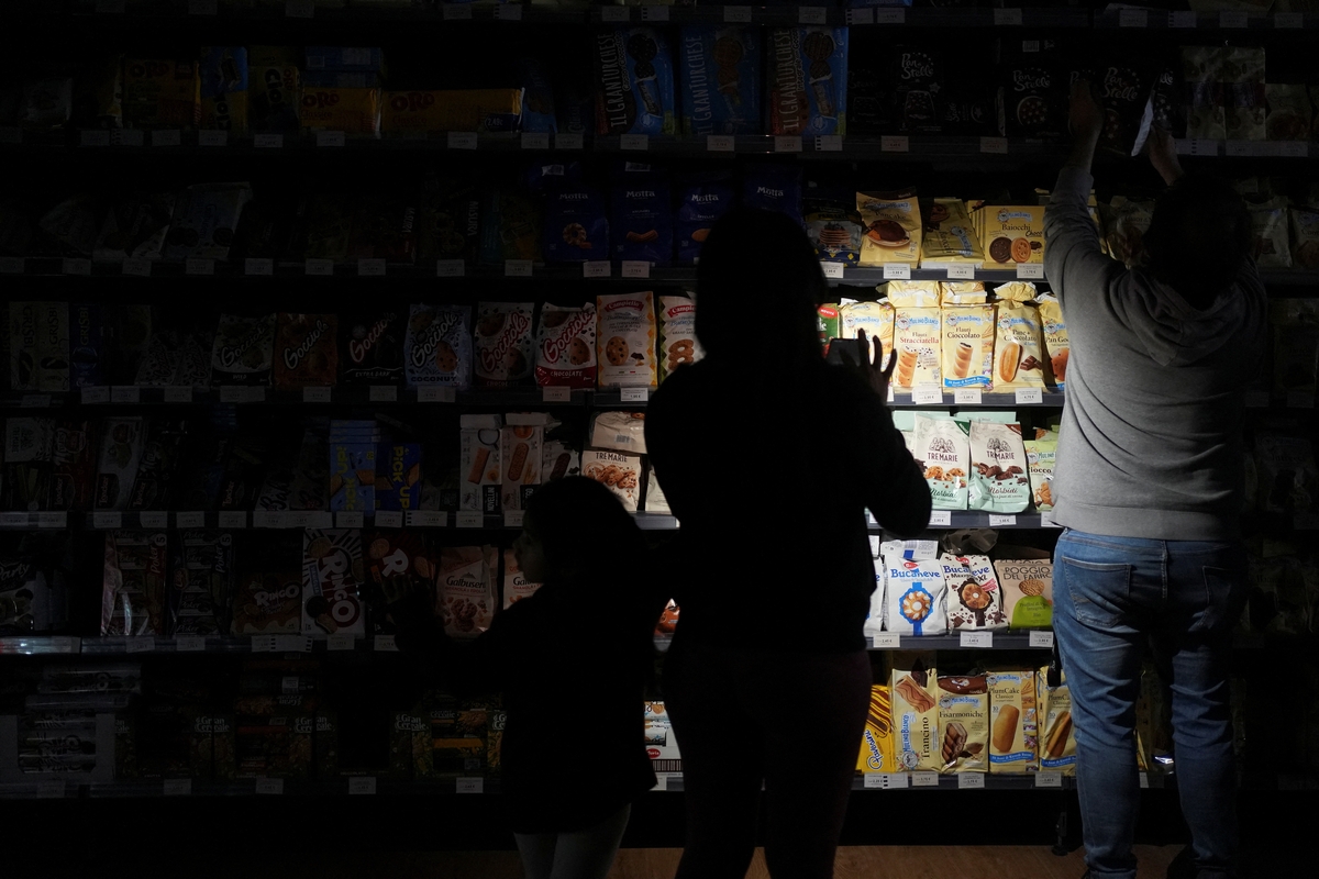 FOTO DE ARCHIVO. La gente usa teléfonos y linternas frontales para comprar en un supermercado durante el apagón en Barcelona, España. 28 de abril 2025. REUTERS/ Bruna Casas