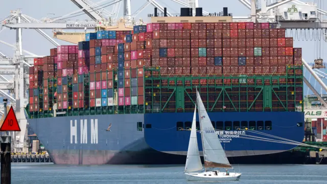 Un velero pasa junto a un buque portacontenedores en el puerto de Oakland, en Oakland, California, EE. UU., el 14 de julio de 2025.