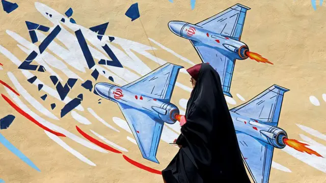Se puede ver a unos drones destrozando una Estrella de David mientras una mujer vestida de negro pasa junto a un mural antiisraelí en Teherán.