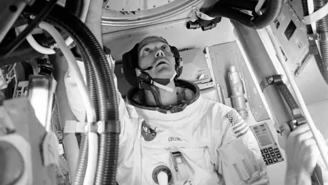 El astronauta Michael Collins mira hacia un portal dentro del módulo del Apolo 11.