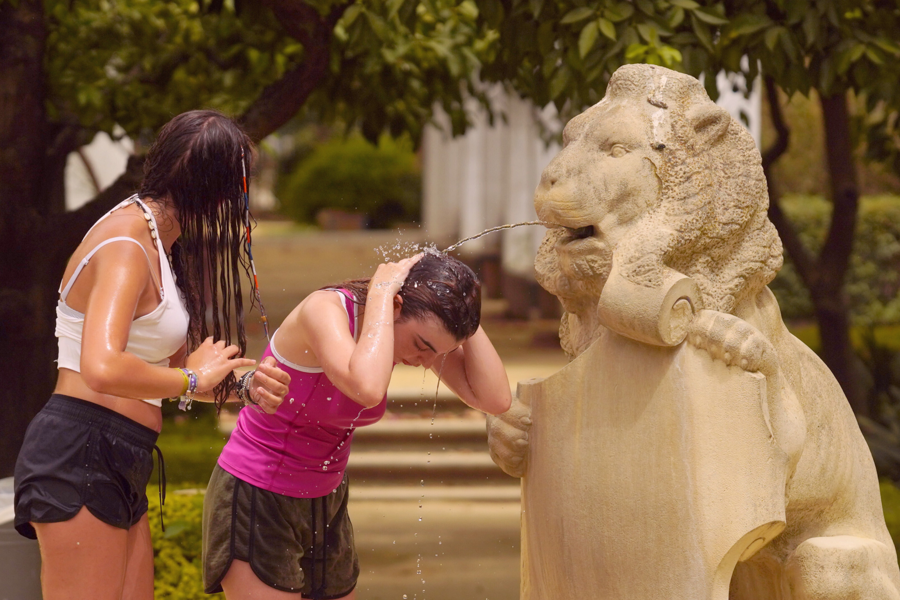 Dos chicas se refrescan por el calor en una fuente de Sevilla.