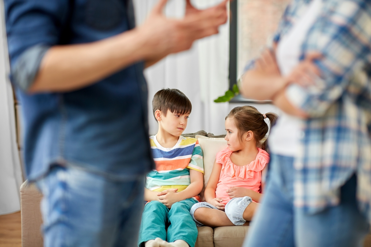 Dos niños en el sofá mientras sus padres discute en una imagen de recurso. (Adobe Stock)