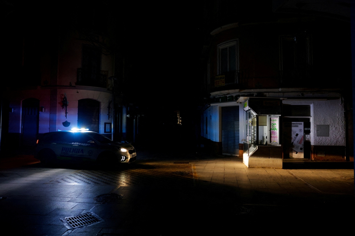 Un coche de la policía local patrulla una calle comercial sin alumbrado eléctrico para evitar robos y saqueos en las tiendas a primera hora de la mañana durante un apagón que afectó a gran parte de España, en Ronda, España 29 de abril de 2025. REUTERS/Jon Nazca/Foto de archivo